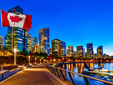 Vancouver bei Nacht mit beleuchteter Skyline, Uferpromenade und kanadischer Flagge