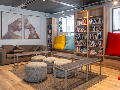 Gemütlicher Gemeinschaftsraum mit Sofas, Sitzhockern und Bücherregal für Sprachschüler