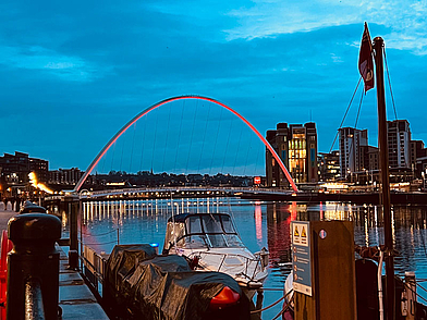 Gateshead Millennium Bridge und Uferpromenade in Newcastle bei Dämmerung