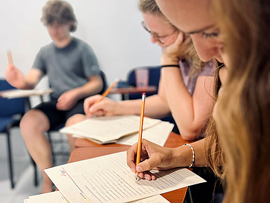 Konzentration beim Spanischlernen in Cartagena, Nahaufnahme von Studenten im Unterricht mit typischen Arbeitsmaterialien.