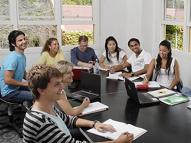 Internationale Sprachschüler lernen Englisch im modernen Klassenzimmer mit Laptop und Arbeitsmaterialien