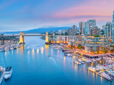 Skyline von Vancouver am Wasser mit Brücke, Yachthafen und Stadtlichtern in der Dämmerung
