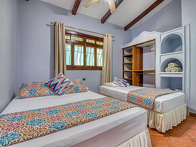 Gemütliches Schlafzimmer in den Villas Verdes Sámara mit zwei Einzelbetten, farbiger Bettwäsche und offenem Kleiderschrank.
