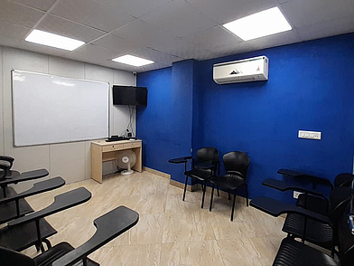 Leerer Klassenraum der ILSC Neu-Delhi mit blauen Wänden, modernen Stühlen und Whiteboard.