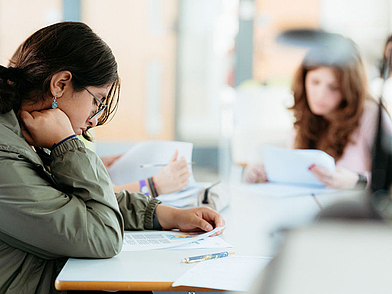 Schülerin in Oxford vertieft sich konzentriert in ein Arbeitsblatt im Unterricht.
