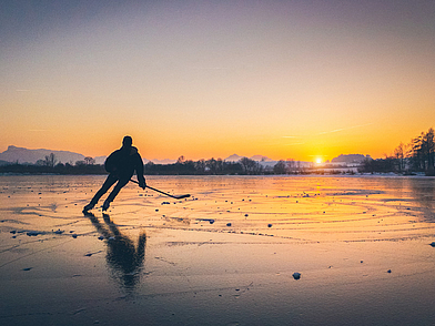 Eishockey auf zugefrorenem See bei Sonnenuntergang als Wintererlebnis einer Sprachreise nach Kanada