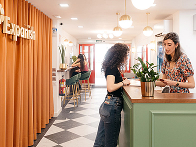 Moderne Rezeption der Expanish Sprachschule in Madrid, an der eine Mitarbeiterin eine neue Sprachschülerin begrüßt.