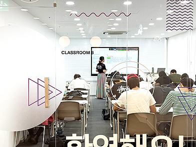 Transparente Klassenzimmer der Lexis Korean School Seoul mit motivierten Sprachschülern im Unterricht.