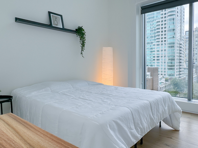 Komfortables Schlafzimmer der CEL Vancouver Unterkunft mit großem Bett und Stadtblick