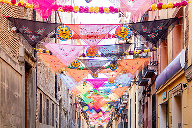 Bunte Tücher schmücken eine Straße in Madrid und zeigen das lebendige Flair in Spanien.