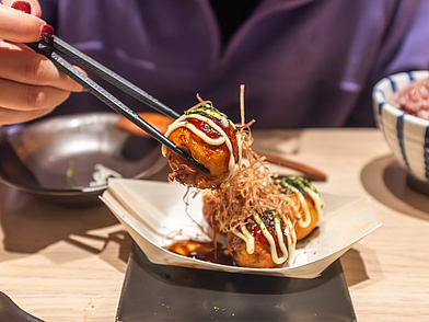 Frische Takoyaki in Japan, serviert mit Stäbchen als kulinarisches Highlight einer Sprachreise