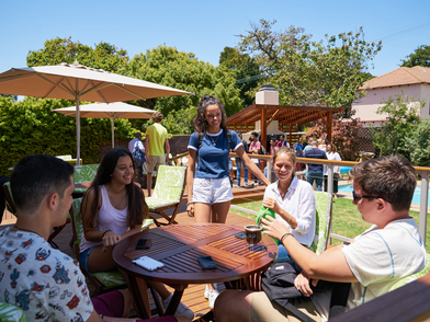 Sprachschüler treffen sich im Garten der Schule, tauschen sich aus und genießen die gemeinsame Zeit nach dem Unterricht.