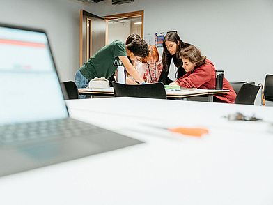 Schülergruppe arbeitet konzentriert an einer gemeinsamen Aufgabe im Englischunterricht.