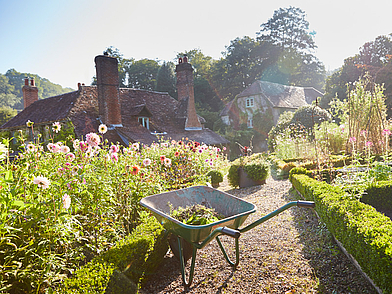 Idyllischer englischer Cottage-Garten mit Blumenbeeten und Schubkarre – Lernumgebung für Englisch-Schüler beim Programm im Haus des Lehrers