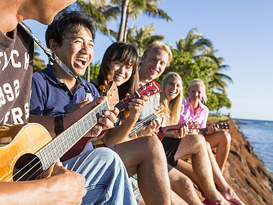Sprachschüler lernen Ukulele am Meer – Englisch lernen und hawaiianische Kultur erleben in Honolulu