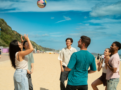 Sprachschüler der Bayswater Bournemouth Sprachschule spielen gemeinsam Volleyball am Strand