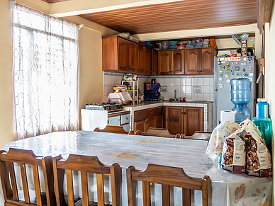 Gemütliche Küche und Essbereich einer Gastfamilie in Sámara mit Holzmöbeln, großem Esstisch und vollständig ausgestatteter Kochzeile.