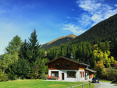 Gemütliches Schülerhaus in Liddes, umgeben von grüner Berglandschaft.