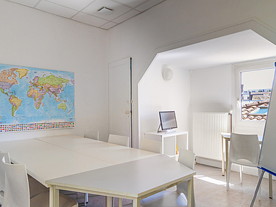 Helles Klassenzimmer mit Weltkarte und Gruppentischen, genutzt für Französisch-Sprachkurse in Bordeaux.